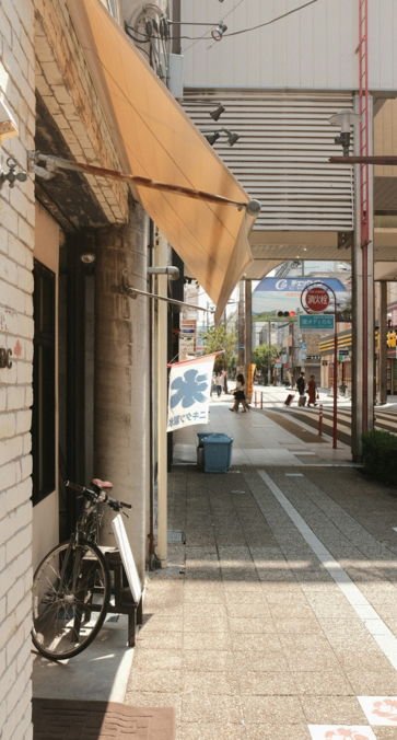 Bicycle parked outside a cafe on a sunny street.